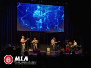 Adult Music Classes band performing live with stage visuals